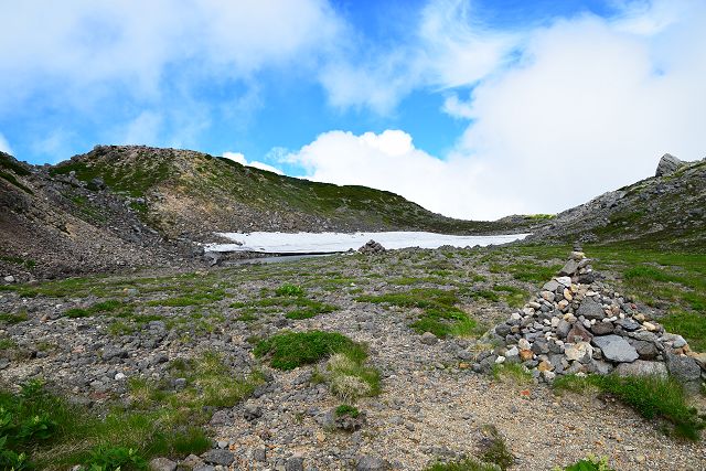 登山道の平たん部から見た油ヶ池と石積みケルン