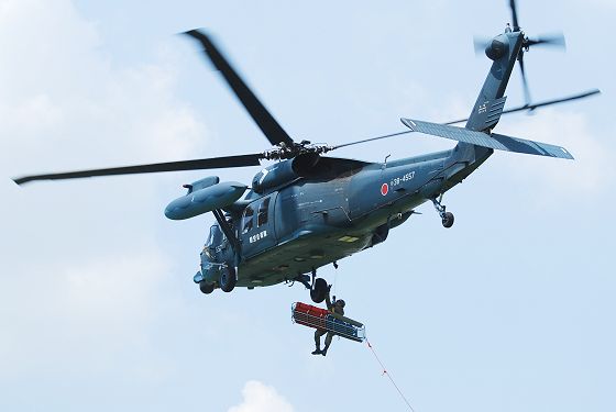 救難飛行展示で救助用ホイストを用いて隊員と担架を吊り上げる救難ヘリコプター UH-60J