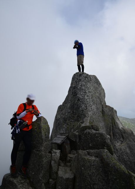 宝剣岳山頂の巨石に立つ登山者