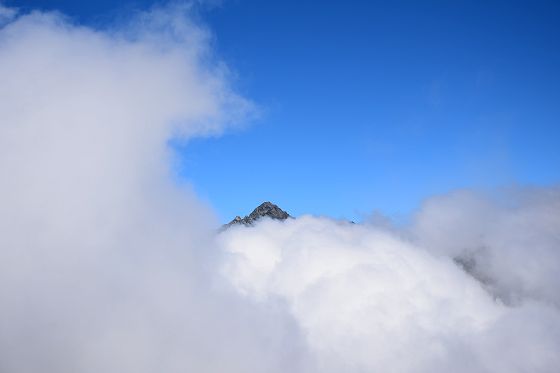 2471メートル鞍部から眺めた雲間に浮かぶ剱岳の山頂部